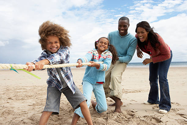 Family having fun playing tug of war on beach